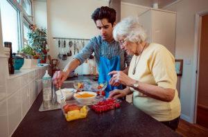 Jongen helpt bejaarde vrouw met koken