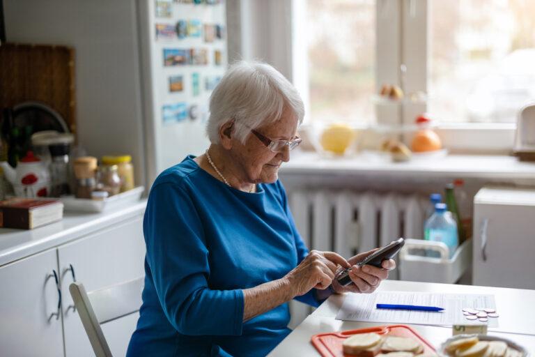 Oudere dame gebruikt thuis haar mobiele telefoon